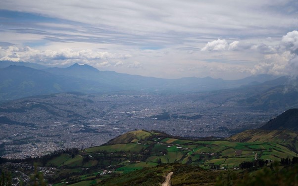 Green Mountains and the city of Quito, Ecuador under white clouds